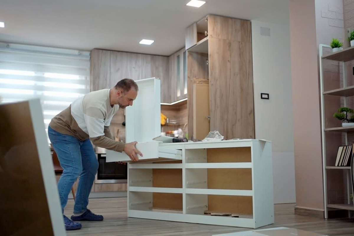 Man assembling white flat-pack cabinet during a home renovation project, illustrating FHA 203(k) loan Texas renovation requirements.